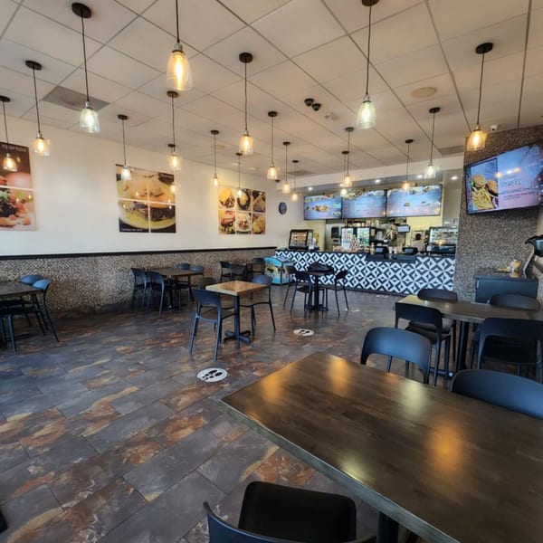 Interior of Eparepa restaurant with tables, chairs, pendant lights, and a service counter with menu screens.