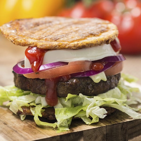 A Venezuelan Eparepa burger with a beef patty, lettuce, tomato, onion, cheese, and ketchup.