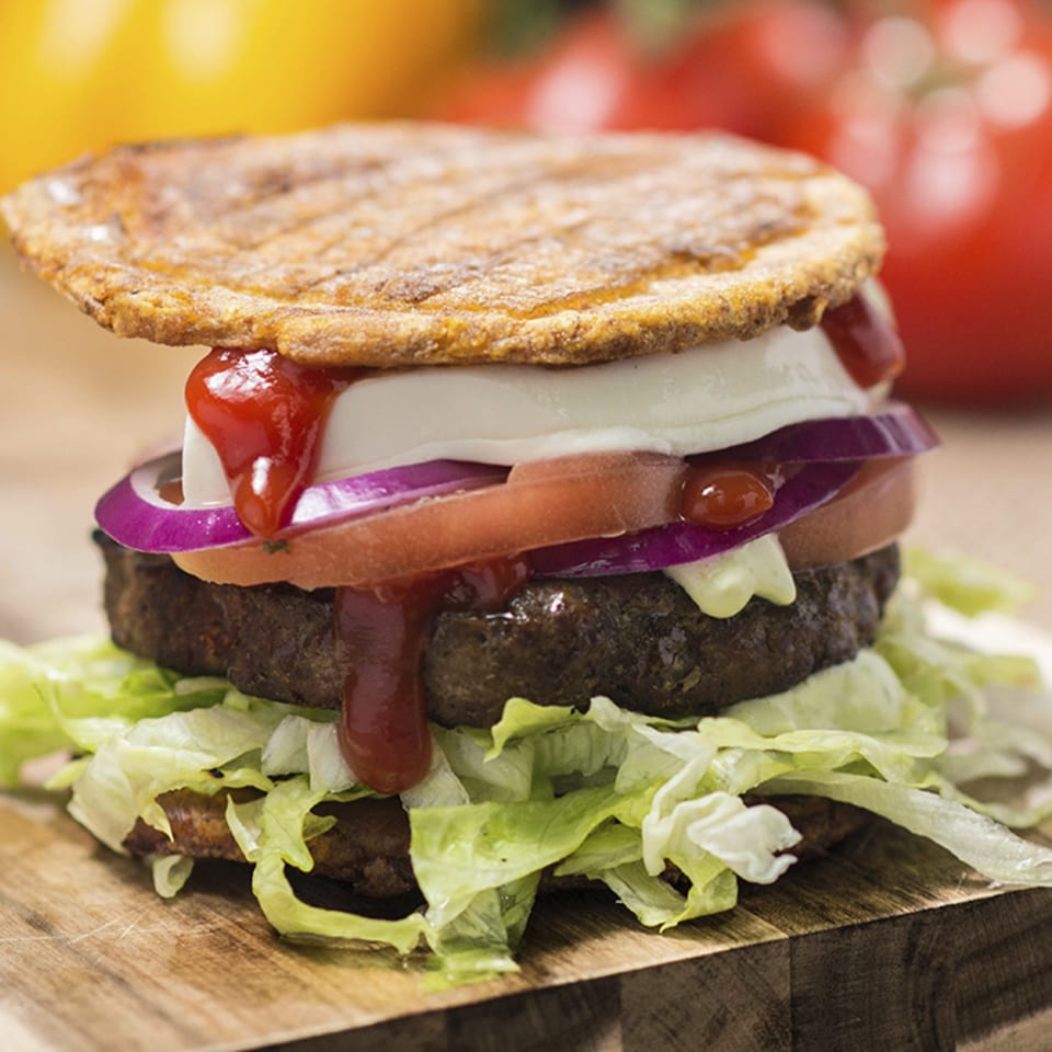 A Venezuelan Eparepa burger with a beef patty, lettuce, tomato, onion, cheese, and ketchup.